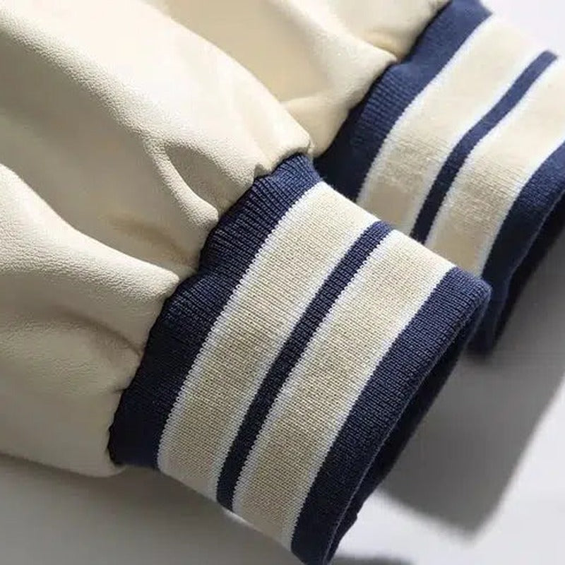 Detail van de gestreepte geribde manchet en de mouw in leerlook van de blauwe varsityjas | Boutique Moda