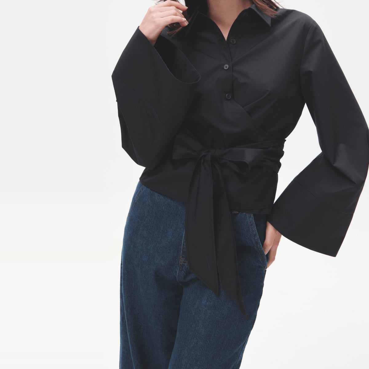Vrouw draagt donkere wikkelblouse met wijde mouwen en strikceintuur, vooraanzicht | Boutique Moda