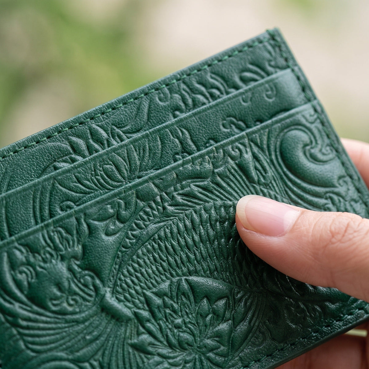 Groene pasjeshouder met reliëfpatroon, vastgehouden in hand, kaartvakken zichtbaar | Boutique Moda