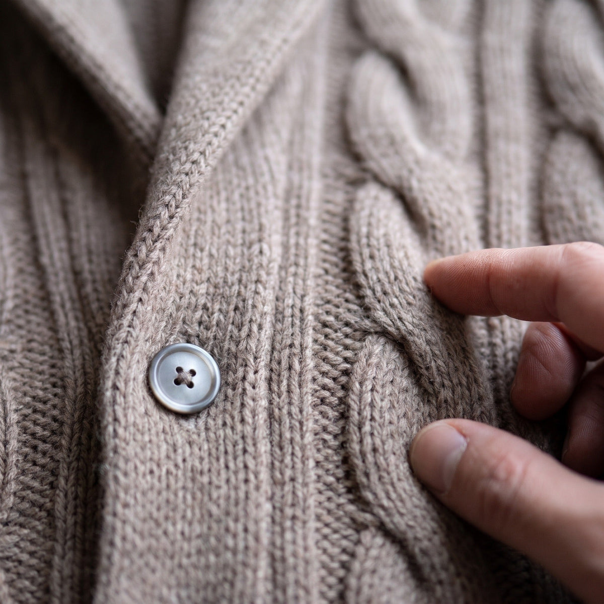Beige vest met kabelbreisel en knoopsluiting, close-up gedragen door een persoon | Boutique Moda