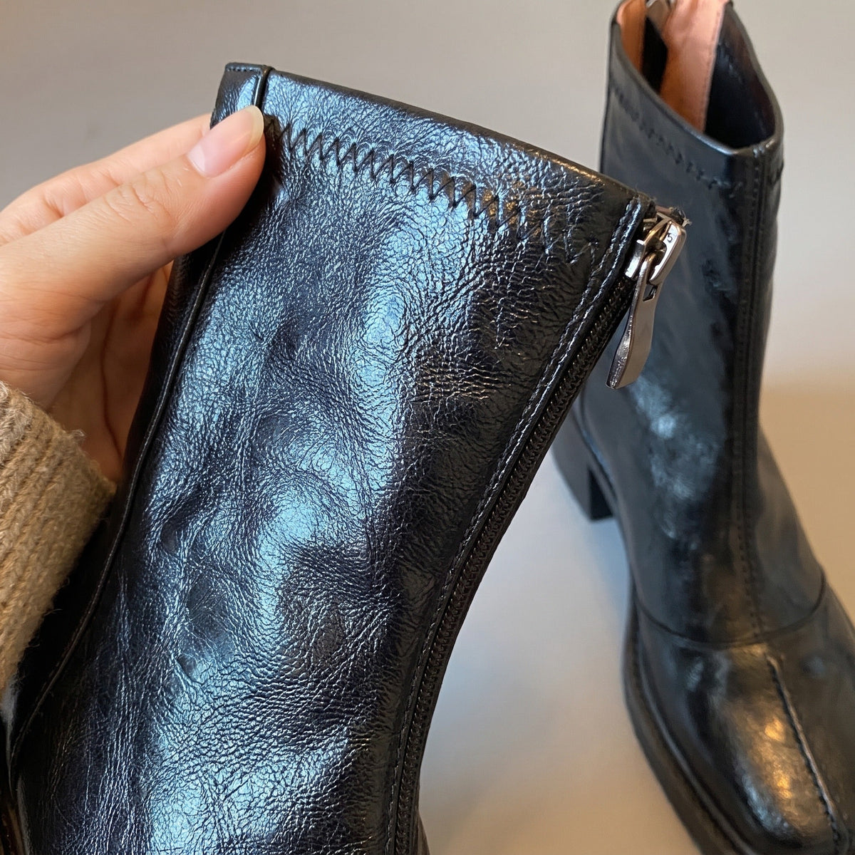Zwarte enkellaars met blokhak, rits en stiksel, gedragen door een persoon | Boutique Moda