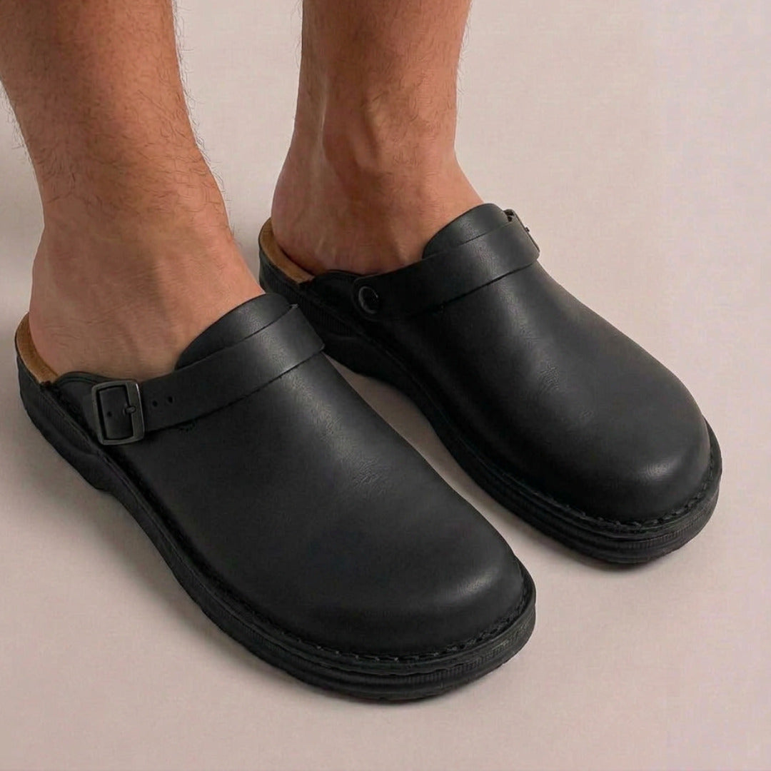 Zwarte vegan leren clogs met gesp, gedragen aan blote voeten | Boutique Moda