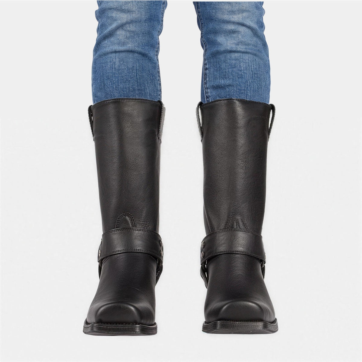 Man in skinny jeans draagt zwarte cowboylaarzen met harnasriem en blokhak, vooraanzicht | Boutique Moda