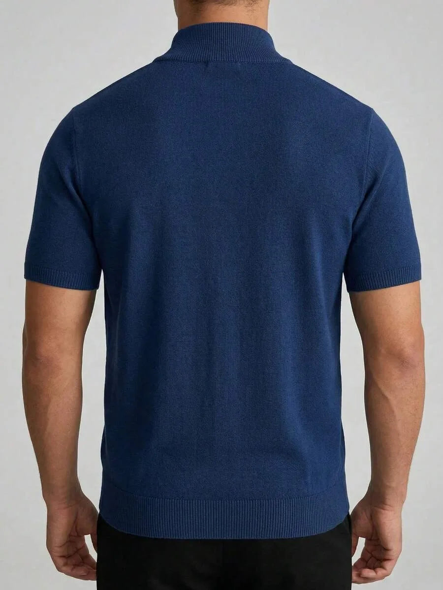 Back view of a man wearing a navy blue short sleeve knit polo shirt with a half-zip collar.
