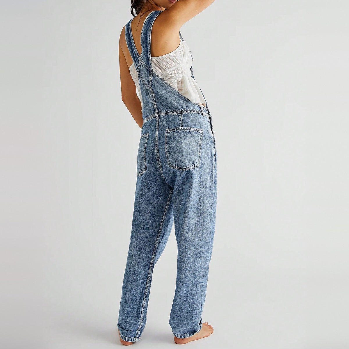 Vrouw draagt lichtblauwe denim tuinbroek met witte top, achteraanzicht | Boutique Moda