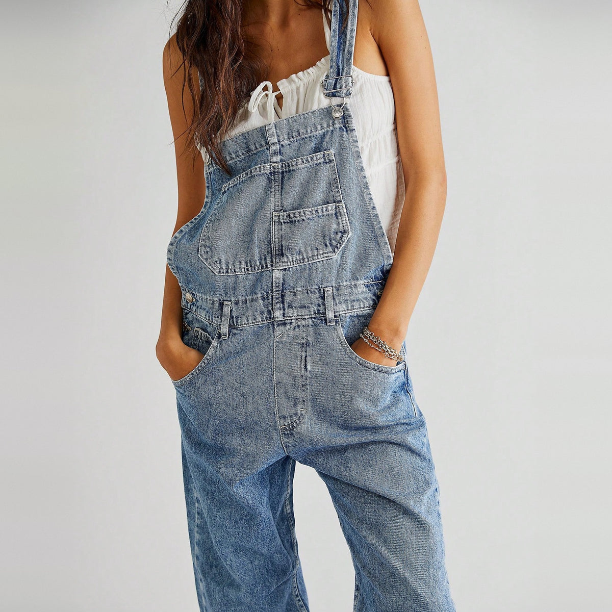 Lichtblauwe denim tuinbroek met zakken, gedragen door vrouw met hand in zak | Boutique Moda