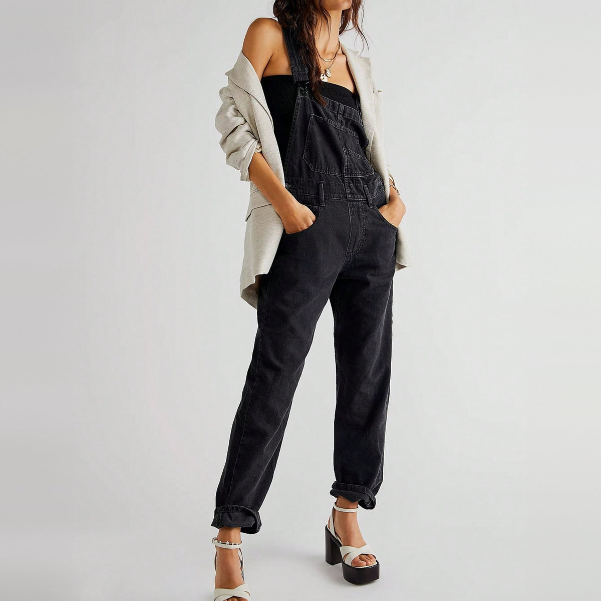 Zwarte denim tuinbroek gedragen door vrouw met witte blazer en hakken | Boutique Moda