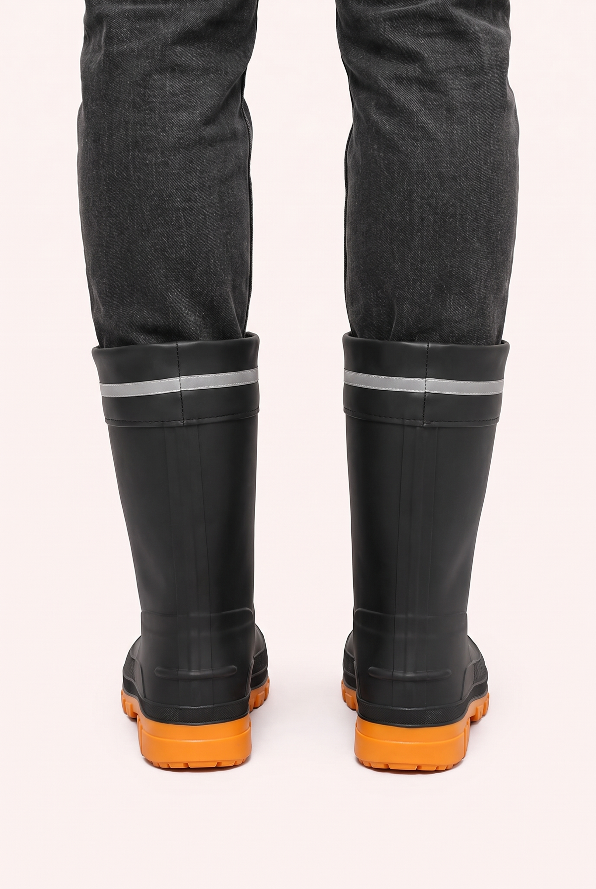 Zwarte regenlaarzen met oranje zool, gedragen door persoon, achteraanzicht | Boutique Moda