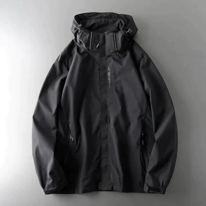 Zwarte windbreaker met capuchon en ritszakken, plat liggend gefotografeerd | Boutique Moda