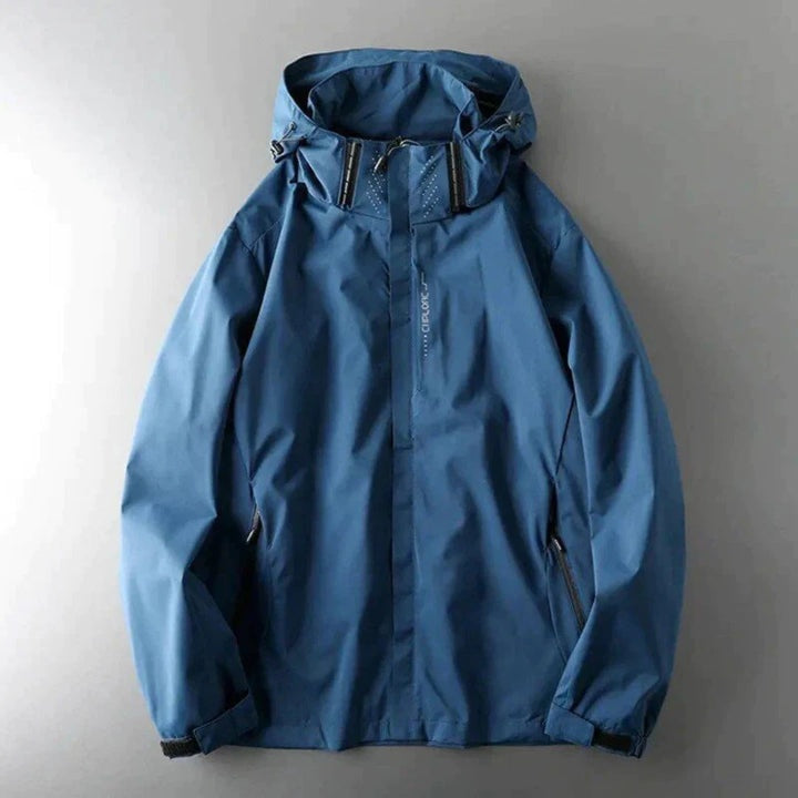 Blauwe windbreaker met capuchon en ritszakken, plat liggend gefotografeerd | Boutique Moda