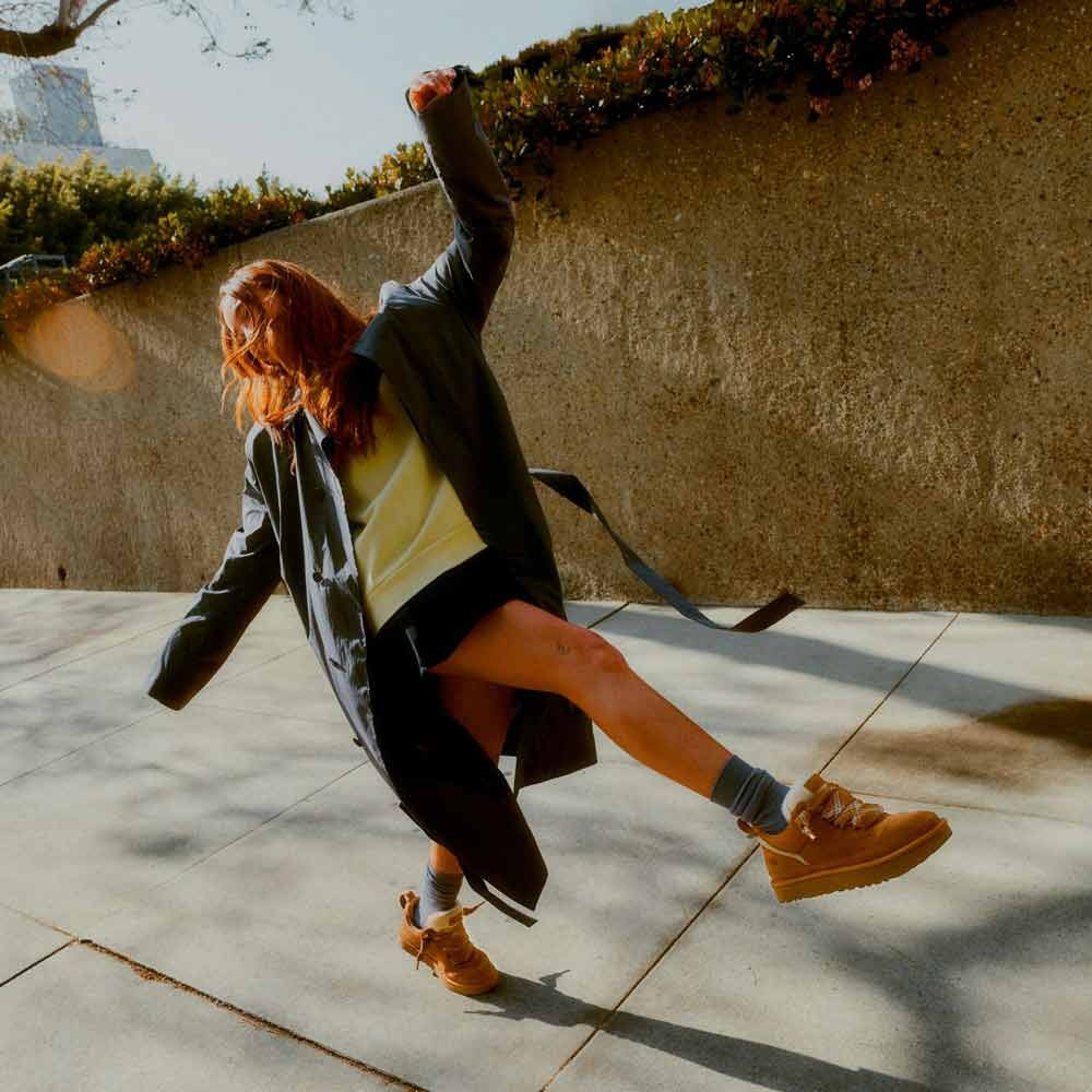 Camelkleurige plateau sneakers gedragen door vrouw tijdens energieke sprong buiten | Boutique Moda