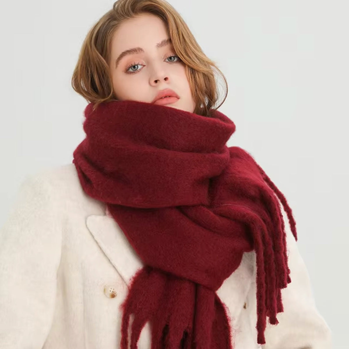 Donkerrode wintersjaal met franjes, effen kleur, gedragen door vrouw in witte jas | Boutique Moda
