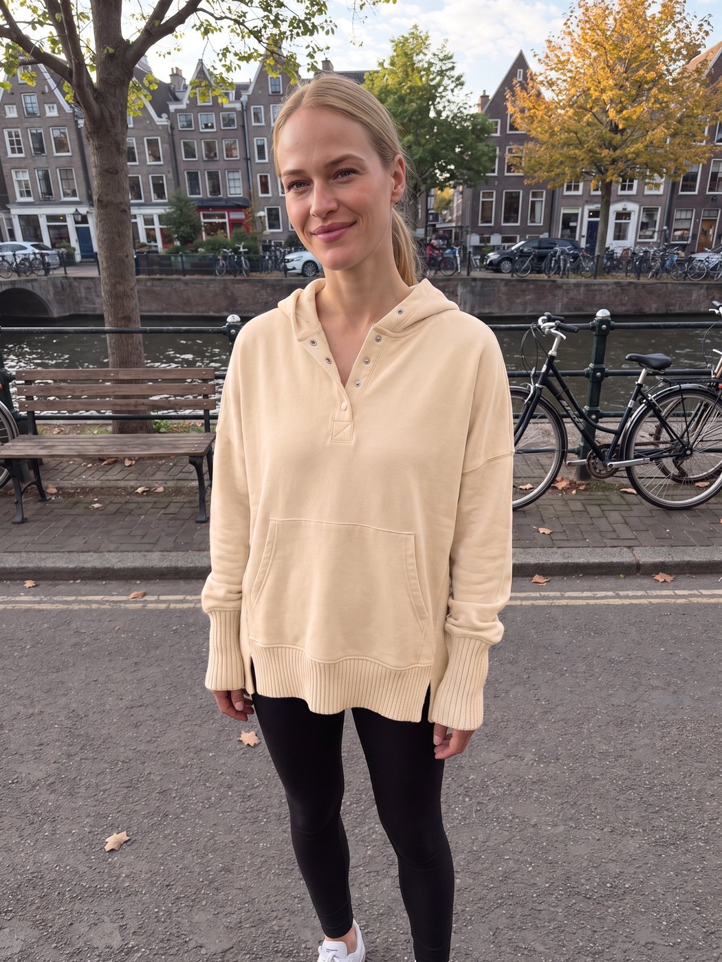 Vrouw draagt de beige oversized trui met capuchon langs een gracht in Amsterdam | Boutique Moda