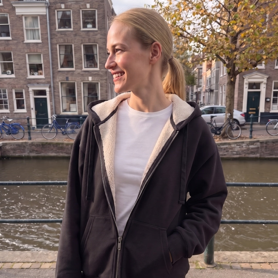 Vrouw draagt het zwarte sweatvest met teddyvoering in een straat in Amsterdam | Boutique Moda
