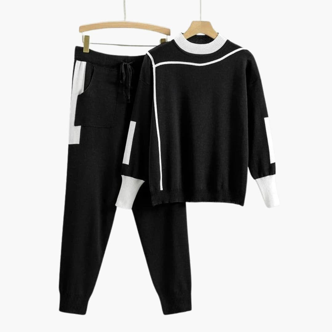 Zwart gebreid joggingpak voor dames met witte contrastbiezen aan een hanger