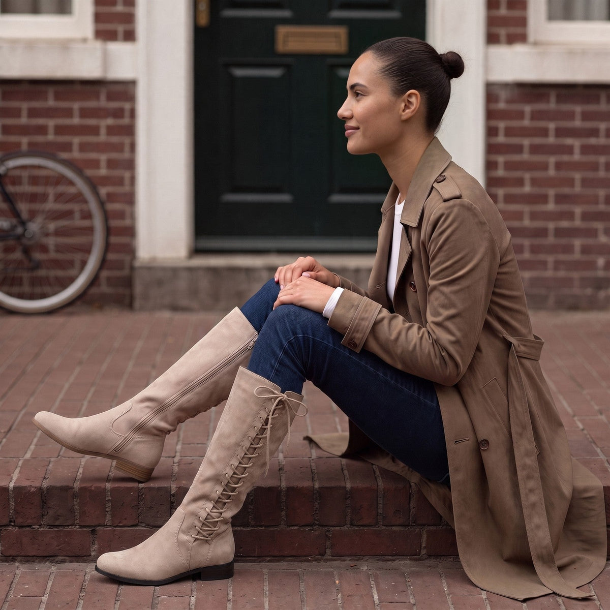 Vrouw op de bakstenen stoep van een Amsterdams grachtenpand in beige knielaarzen met veters aan de zijkant