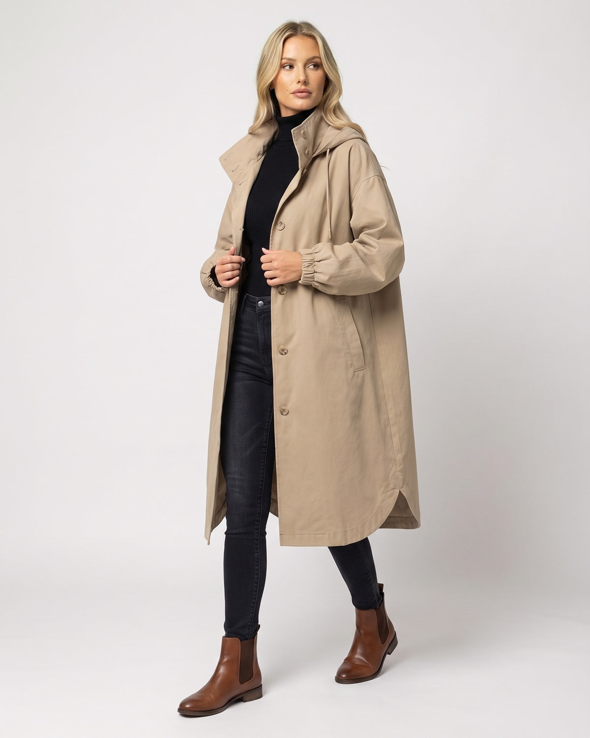 Beige lange parka jas met capuchon en opstaande kraag, open gedragen door blonde vrouw | Boutique Moda