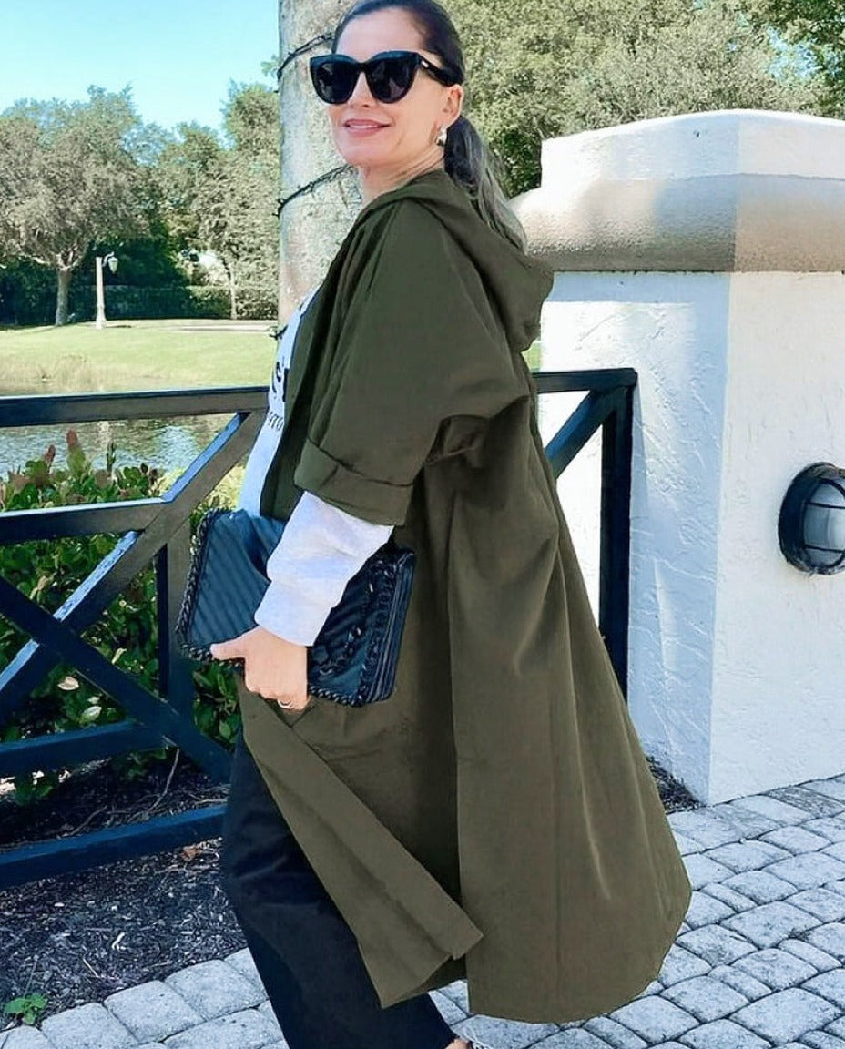 Vrouw draagt lange olijfgroene regenjas met capuchon buiten gefotografeerd | Boutique Moda