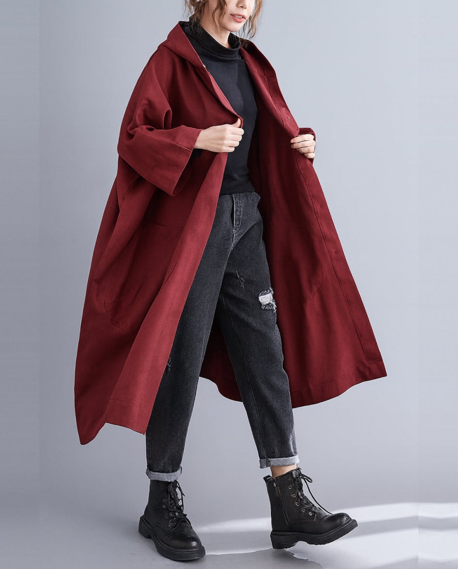 Bordeauxrode oversized regenjas met capuchon, gedragen door vrouw met spijkerbroek | Boutique Moda