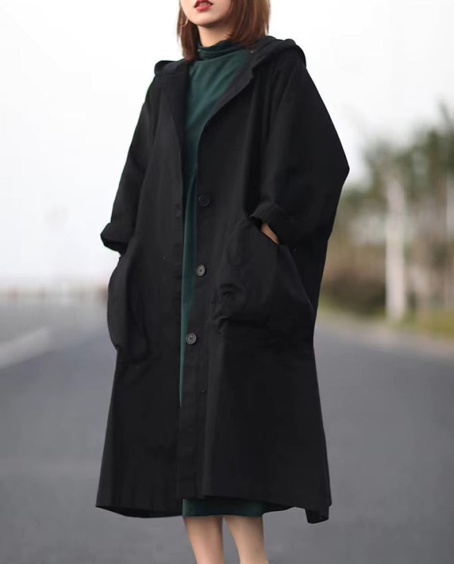 Zwarte oversized regenjas met capuchon, gedragen door vrouw op straat | Boutique Moda