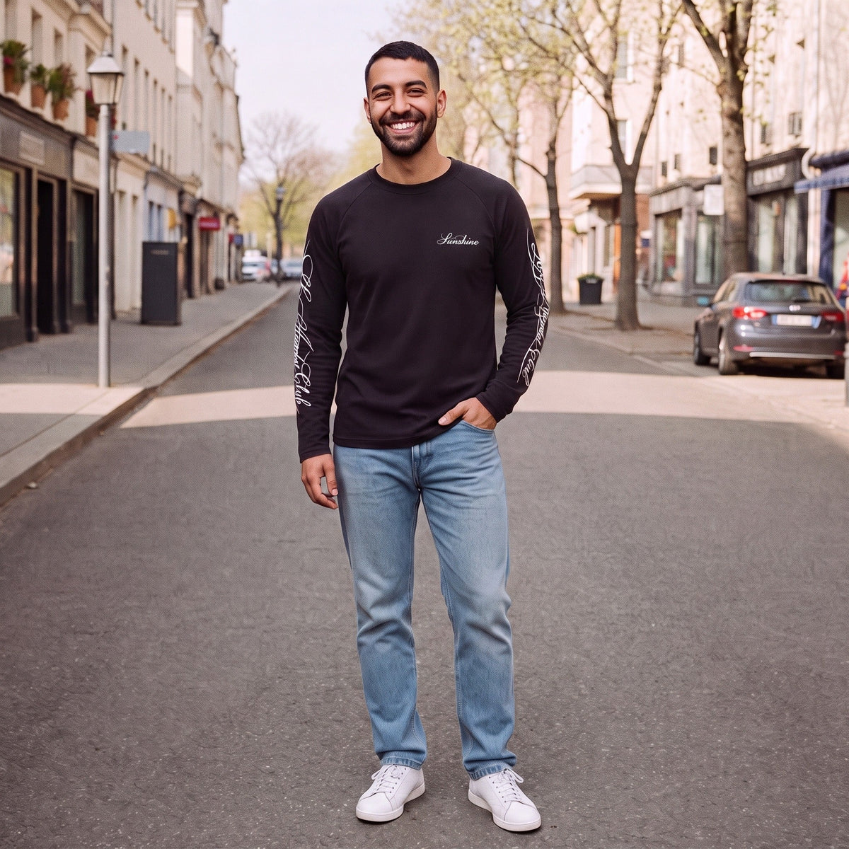 Man draagt zwarte longsleeve met tekst op mouw, staand op straat | Boutique Moda