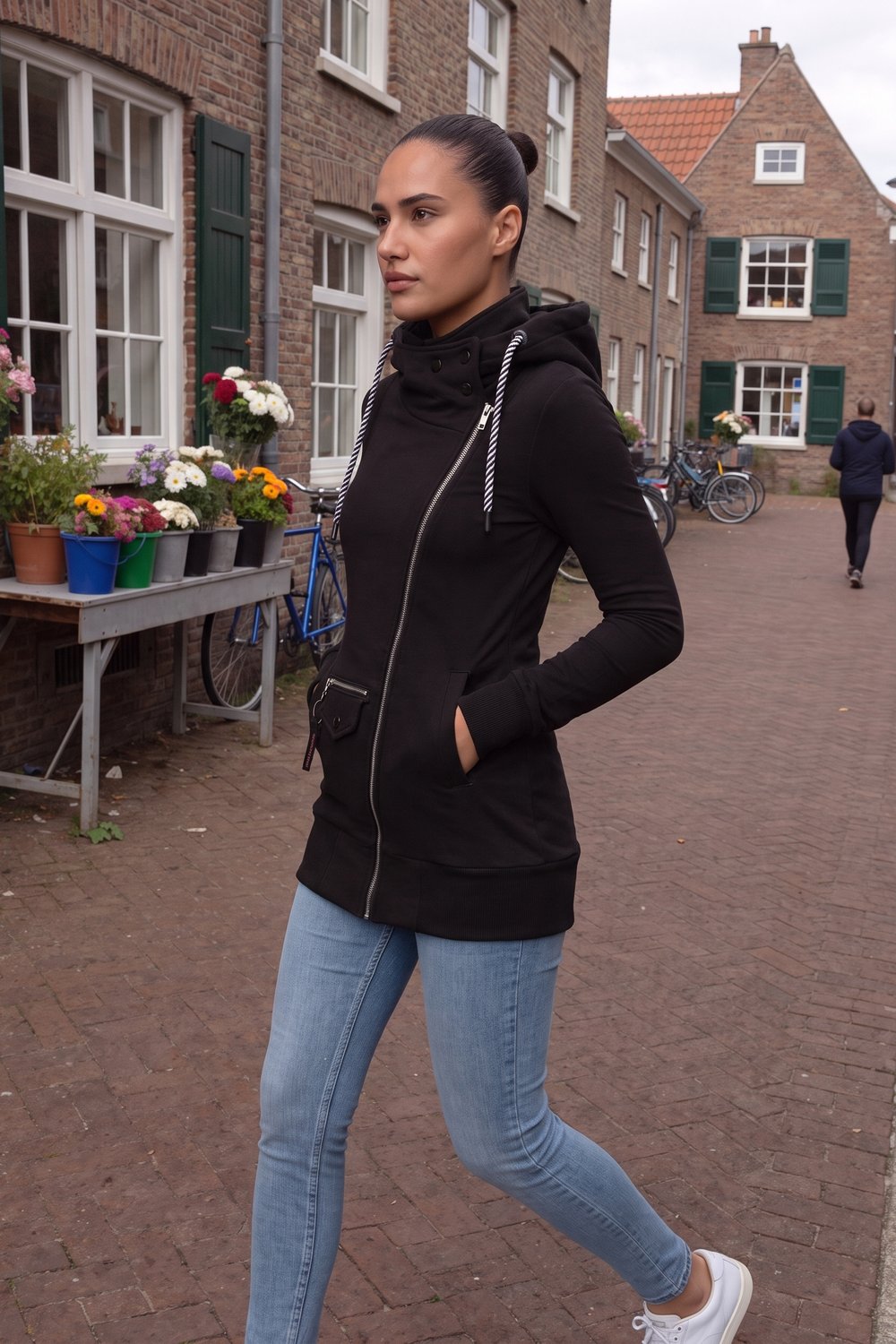 Vrouw in een lange zwarte hoodie met rits op straat in Utrecht