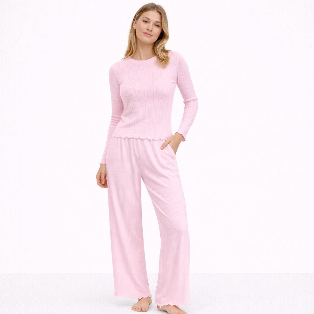 Vrouw in een roze pointelle pyjama set met lange mouwen en wijde broek