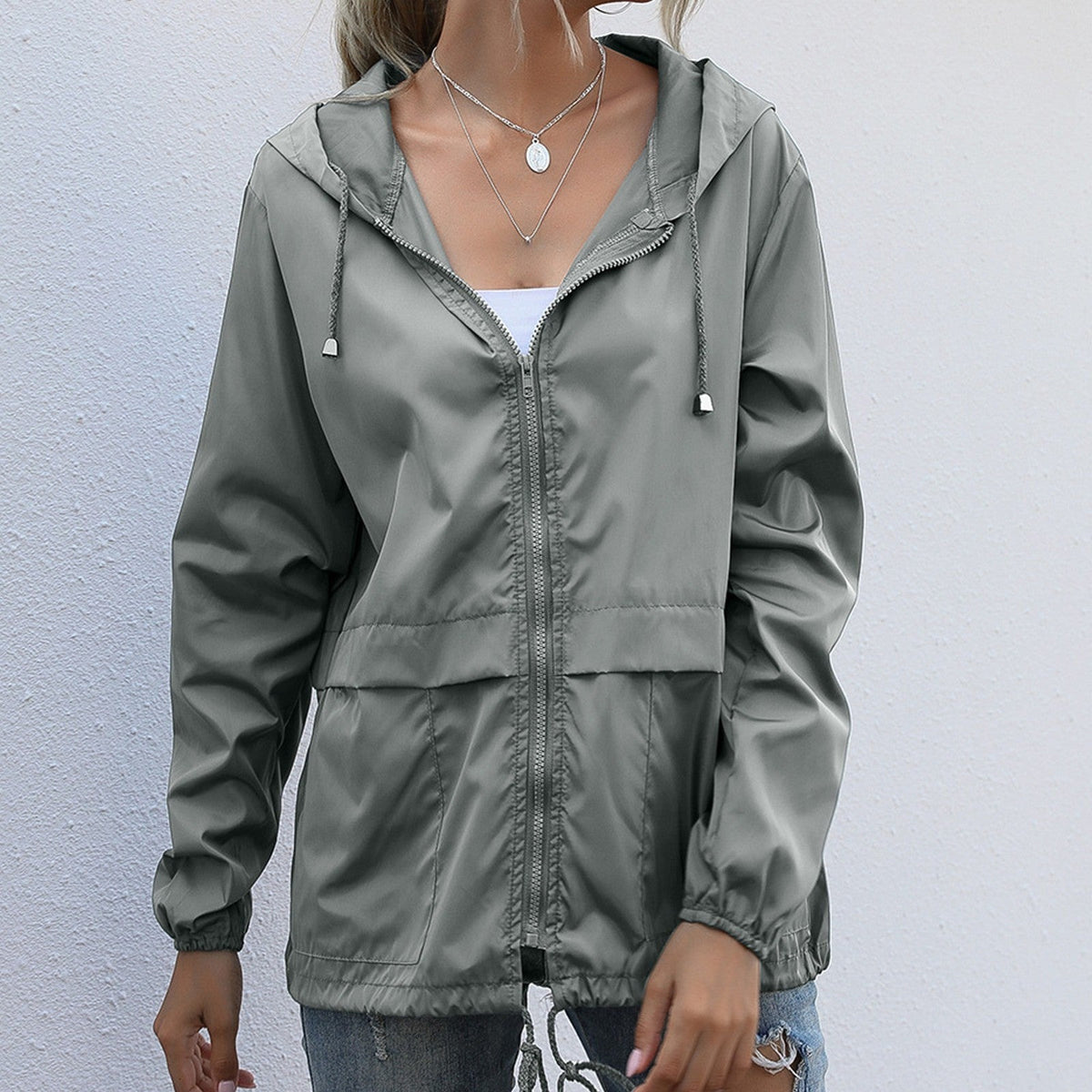 Grijsgroene lichte waterdichte regenjas met capuchon en koord aan de zoom | Boutique Moda