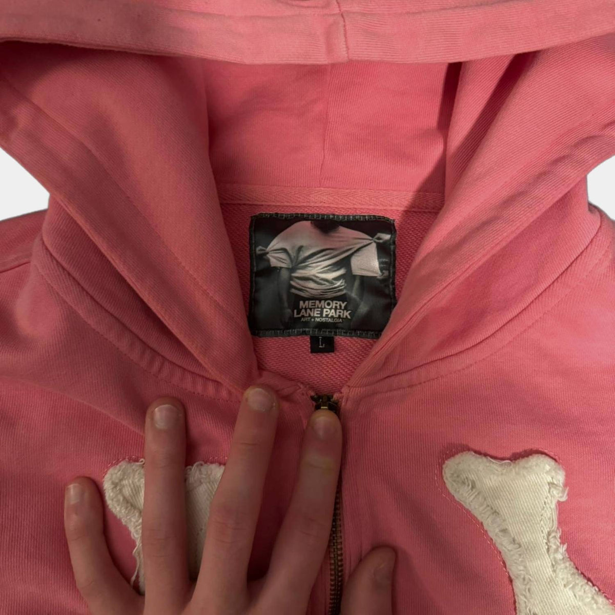 Close-up van het neklabel en de rits op de roze hoodie | Boutique Moda