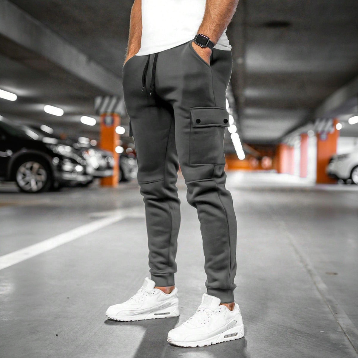 Donkergrijze joggingbroek met cargozak, gedragen door een man in parkeergarage | Boutique Moda