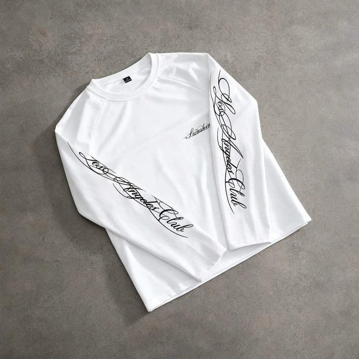 Witte longsleeve plat gefotografeerd met sierlijke handschrift print op mouwen | Boutique Moda