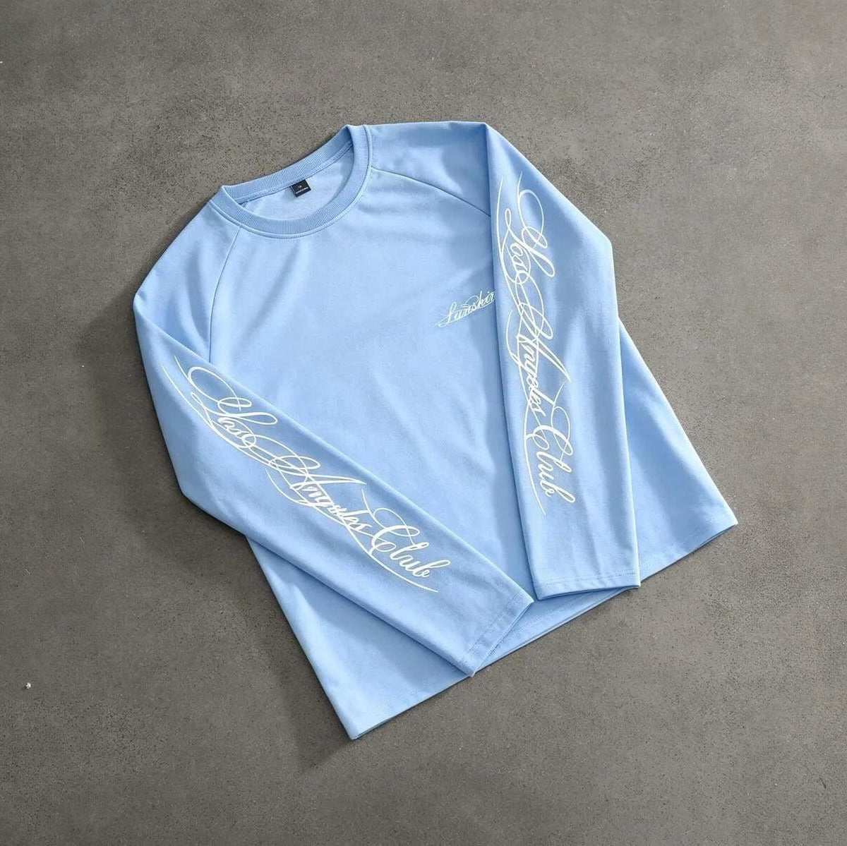 Lichtblauwe longsleeve met handschrift print op mouwen, plat gefotografeerd | Boutique Moda