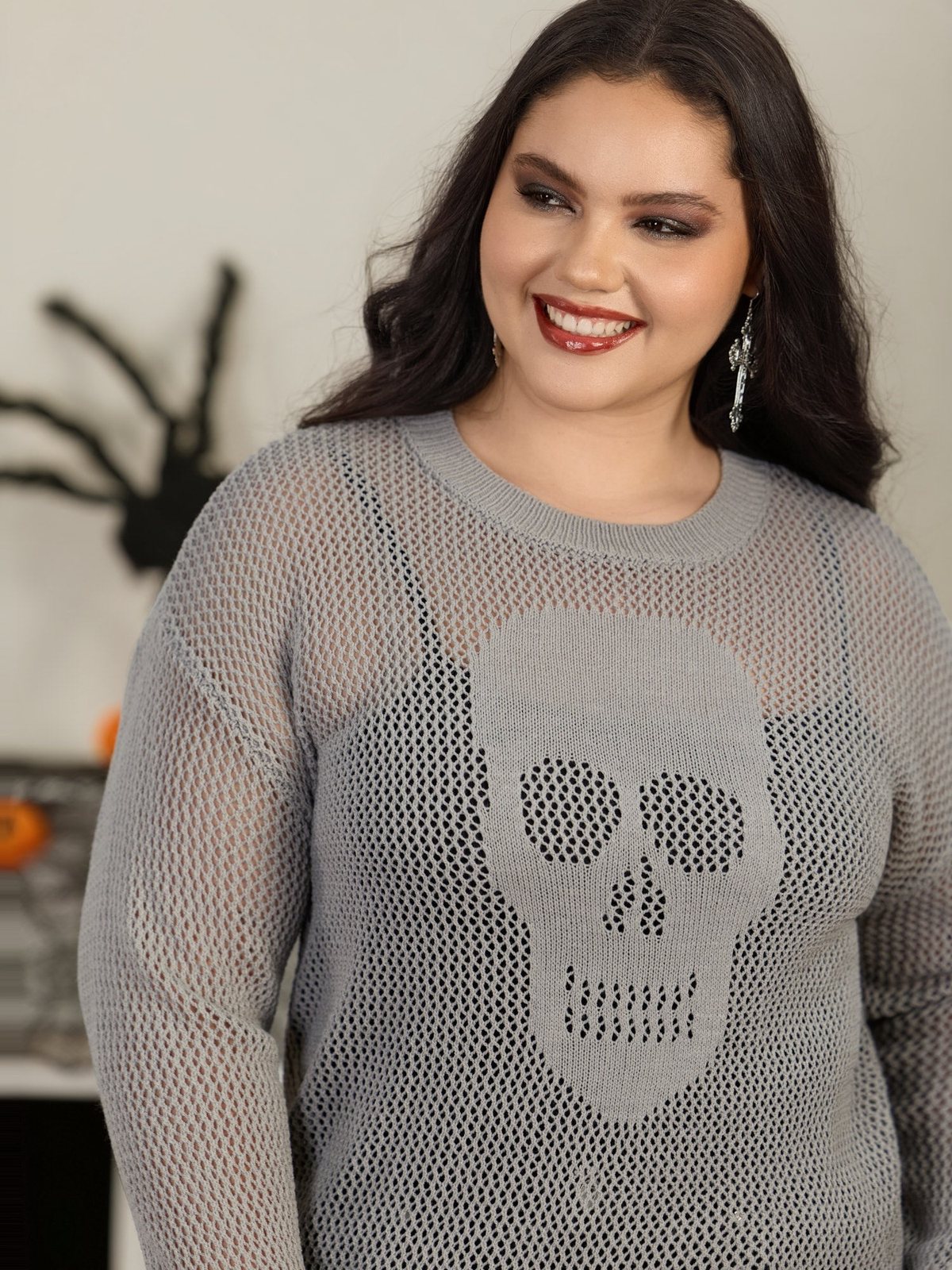Vrouw in de grijze opengebreide trui met doodshoofd op een Halloweenfeest