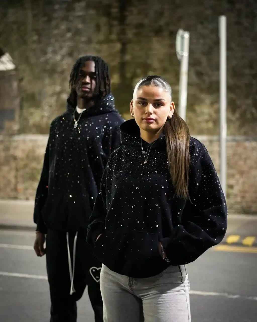 Een man en een vrouw in de zwarte oversized hoodie met steentjes