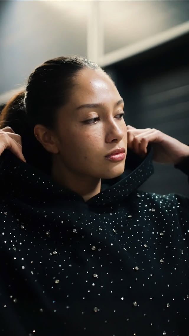 Vrouw trekt de capuchon van de zwarte hoodie met strass omhoog, close-up