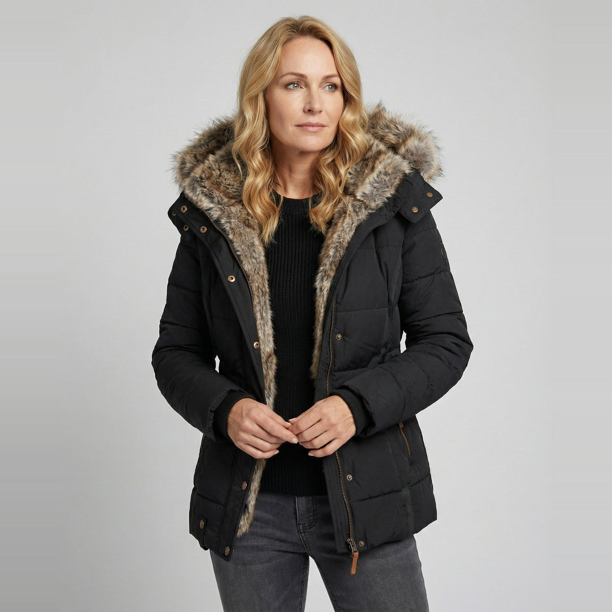 Zwarte winterparka met imitatiebont capuchon, gedragen door blonde vrouw | Boutique Moda