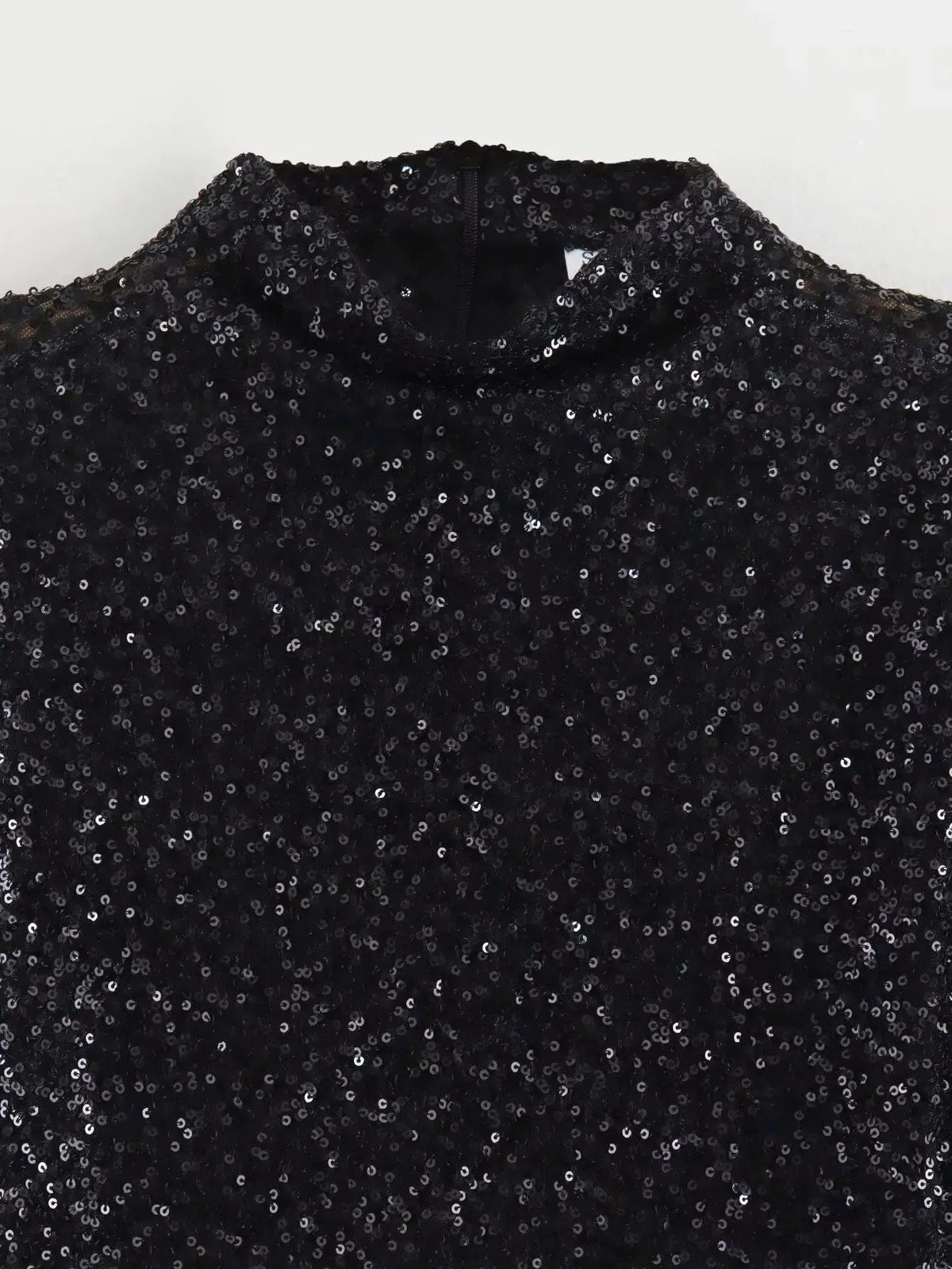 Close-up van de hoge hals en de zwarte paillettenstof van de mini jurk | Boutique Moda