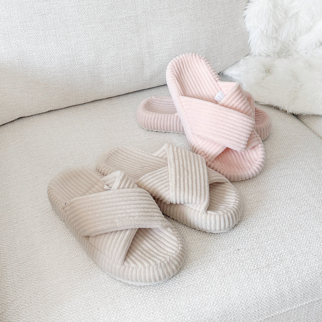 Roze en beige ribfluwelen pantoffels met gekruiste banden op de bank