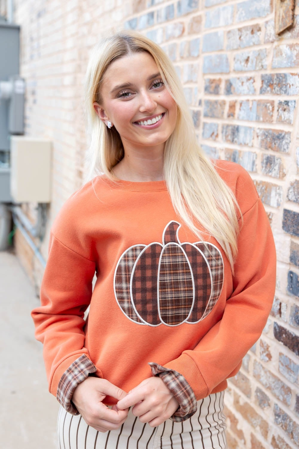 Oranje sweater met geruite pompoenapplicatie