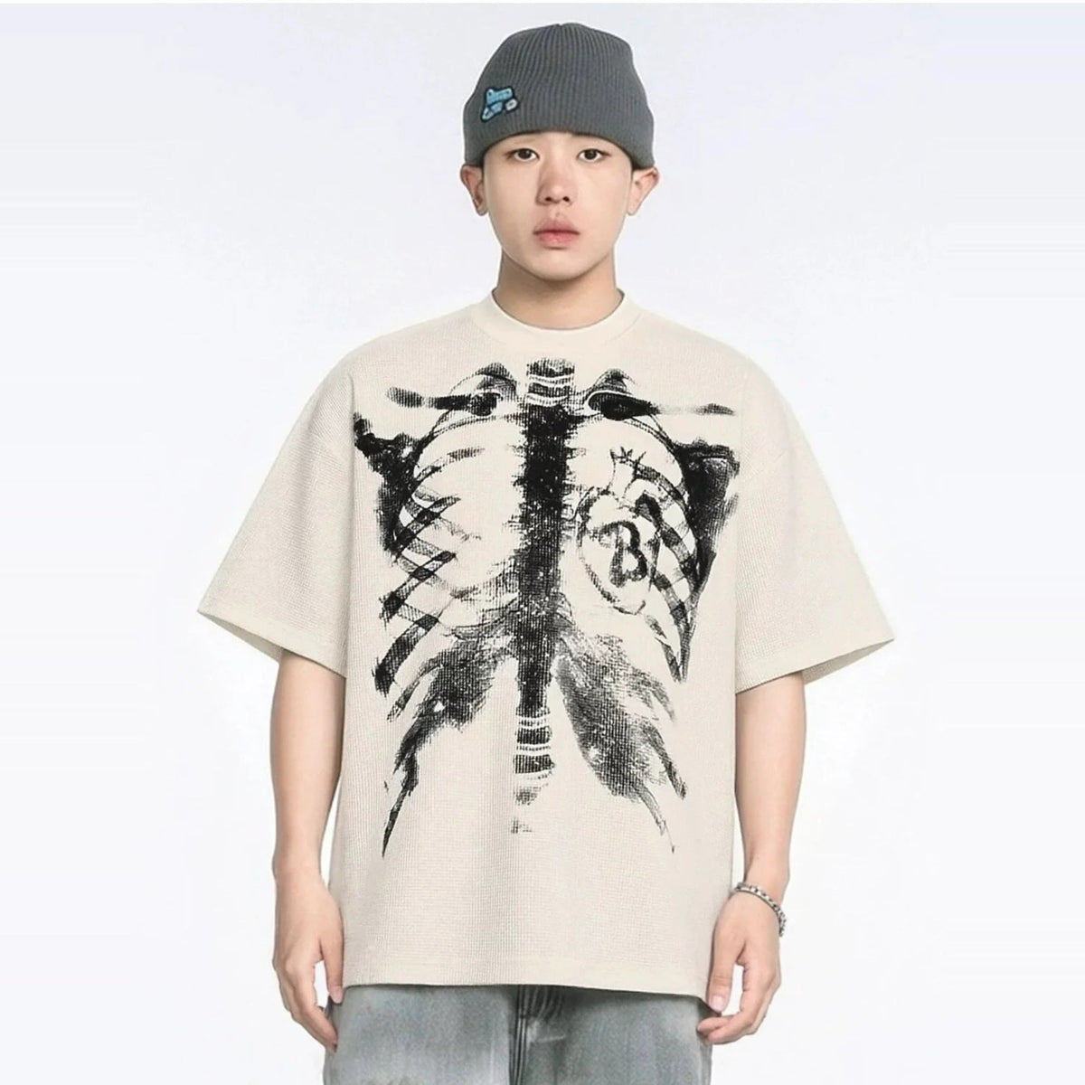 Beige oversized T-shirt met skelet- en hartprint, gedragen door een man | Boutique Moda