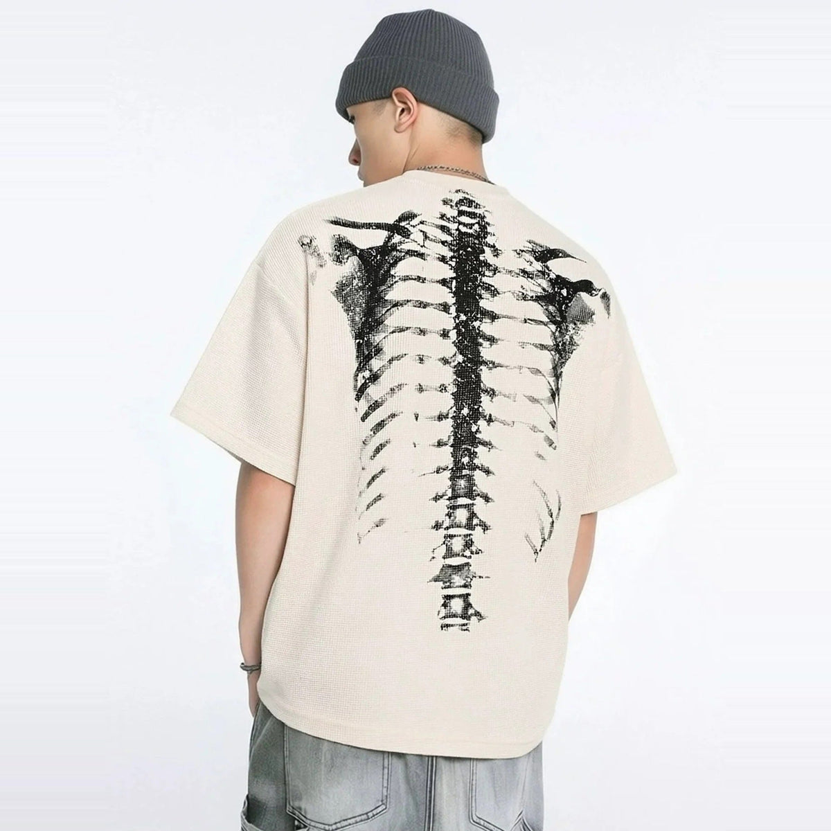 Beige oversized T-shirt met zwarte skeletprint op de rug, gedragen door model | Boutique Moda