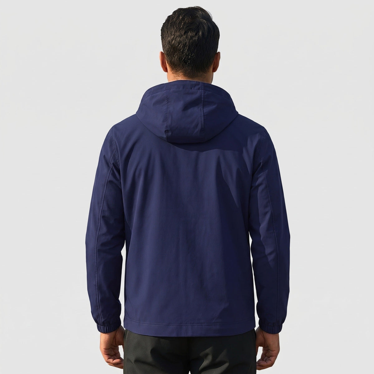 Donkerblauwe regenjas met capuchon, achteraanzicht, gedragen door man | Boutique Moda