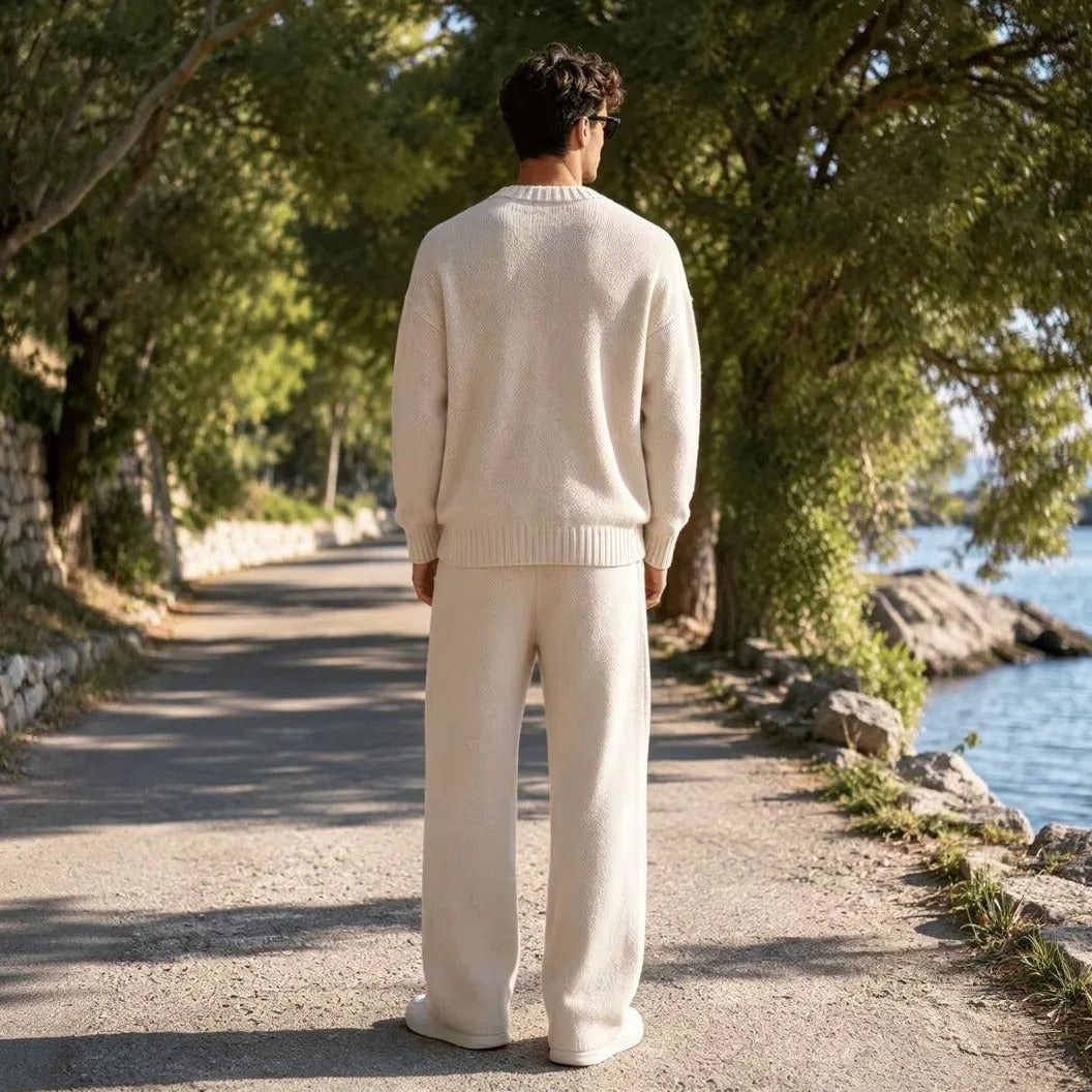 Man draagt crème gebreide trui met wijde broek, wandelend buiten | Boutique Moda