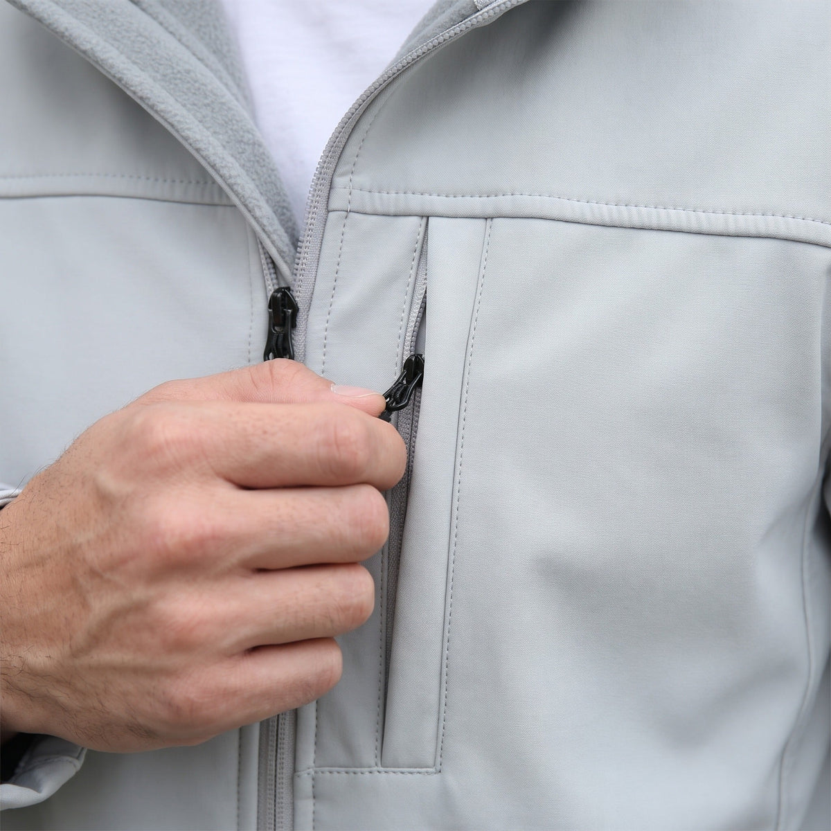 Grijze softshell jas met ritszak, close-up getoond, gedragen door een persoon | Boutique Moda
