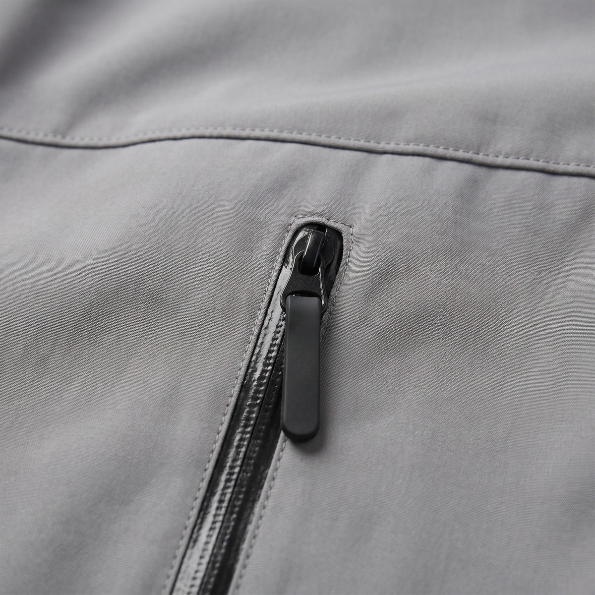 Close-up van grijze jas met zwarte ritssluiting op zak | Boutique Moda