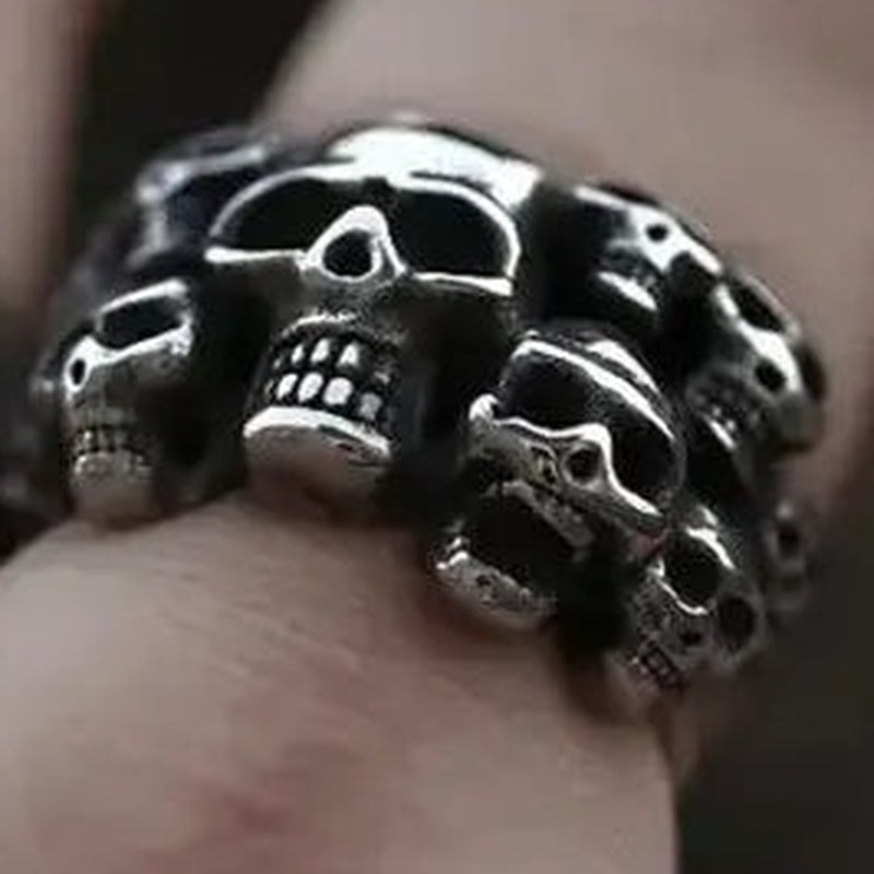 Zilverkleurige ring met meerdere schedels, gedragen aan vinger van hand | Boutique Moda