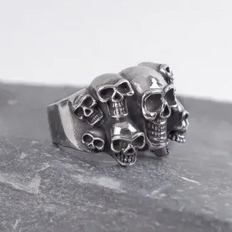 Zilverkleurige ring met meerdere schedels, los liggend op stenen ondergrond | Boutique Moda