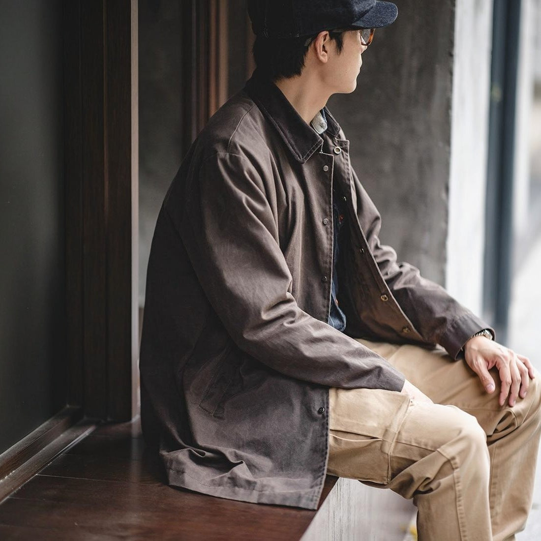 Man draagt bruine jas met corduroy kraag, zittend bij raam | Boutique Moda