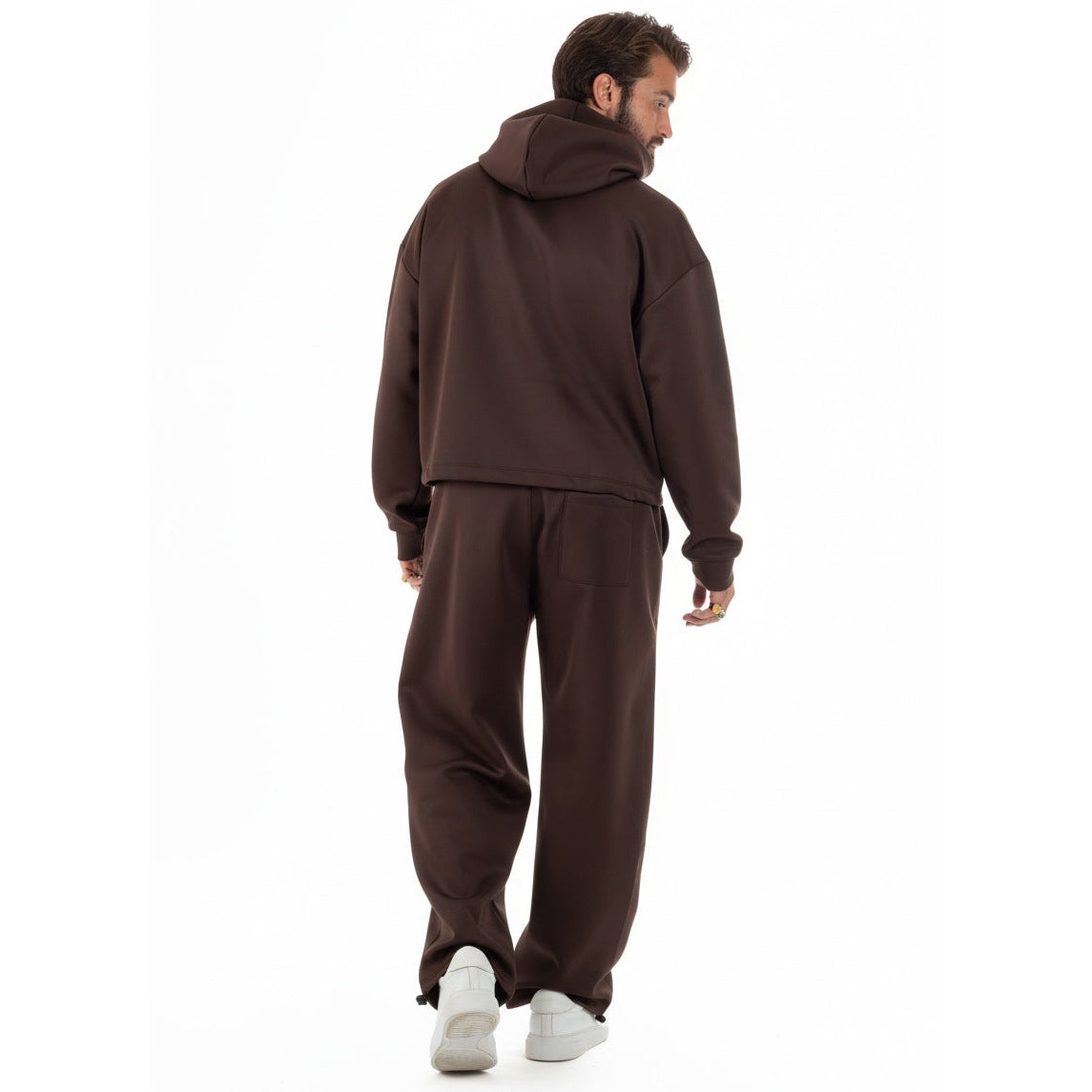 Man draagt bruine cropped hoodie met wijde broek, achteraanzicht | Boutique Moda