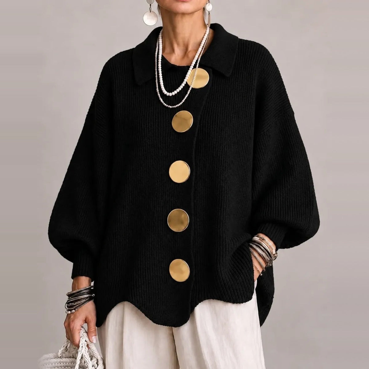 Zwart gebreid vest met gouden knopen, gedragen door vrouw, golvende zoom | Boutique Moda